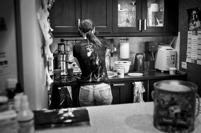 Tanya is washing the dishes. On her T-shirt there is a portrait of her favorite pet Caesar